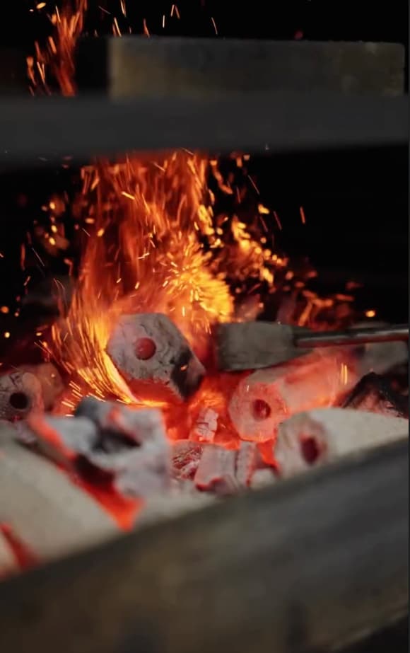 Glowing charcoal embers and open fire cooking at Ember